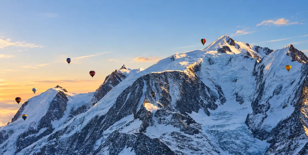 Montgolfières volant au-dessus des sommets enneigés du Mont-Blanc lors du coucher de soleil
